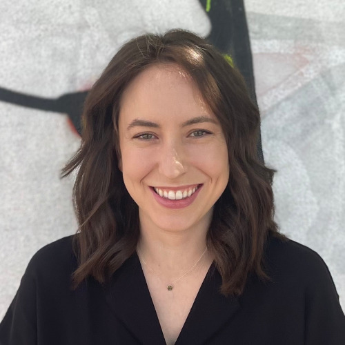 Person smiling standing in front of a wall